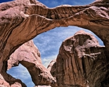 A pair of massive stone arches majestically bow to make openings within openings.  Not every color of the rainbow, the hews tend to browns and reds with that bit of black streak.  An amazing sight in Arches National Park, UT.